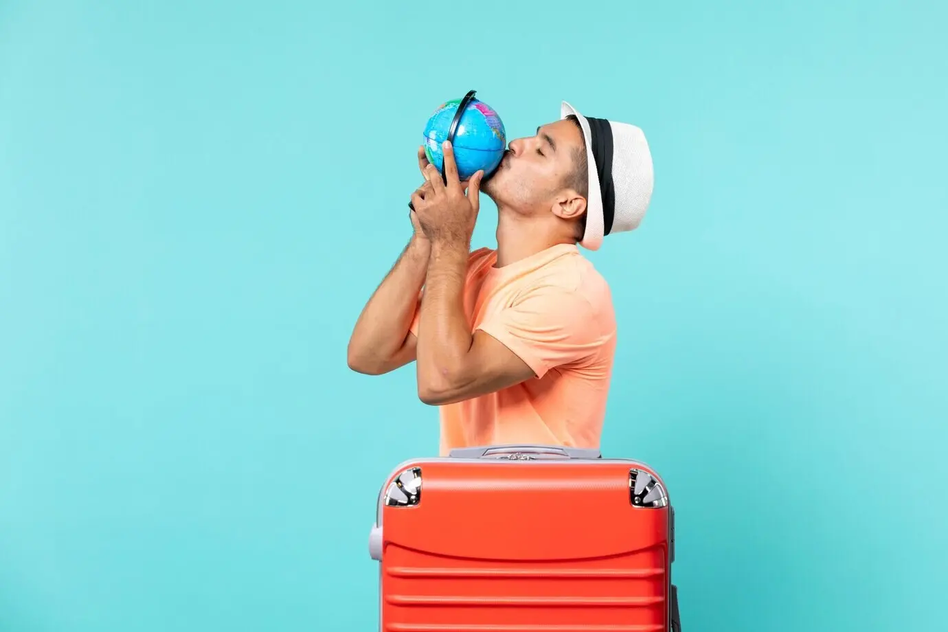 Mann im Urlaub hält einen kleinen Globus vor blauem Hintergrund.